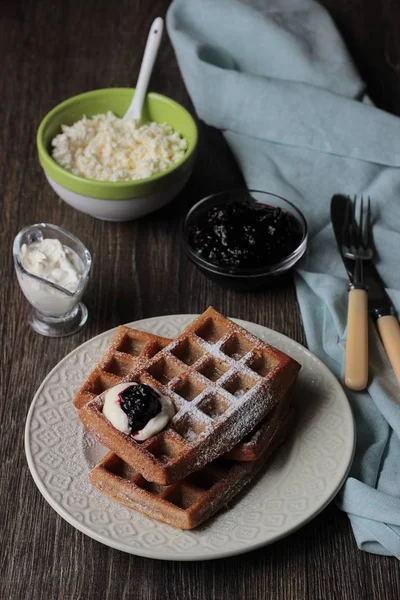 Pudra şekeri ve ahşap masa üzerinde krema ile geleneksel Belçika waffle. Gurme kahvaltı. 