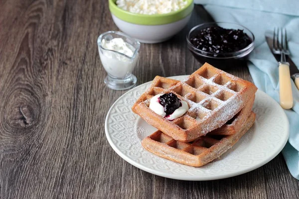 Pudra şekeri ve ahşap masa üzerinde krema ile geleneksel Belçika waffle. Gurme kahvaltı. 
