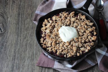 Berry ile yulaf ezmesi gevrek kabuk ahşap arka plan üzerinde dökme demir tavada kremalı kek. Sağlıklı kahvaltı.