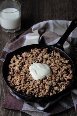 Berry ile yulaf ezmesi gevrek kabuk ahşap arka plan üzerinde dökme demir tavada kremalı kek. Sağlıklı kahvaltı.