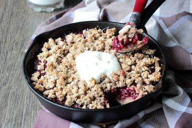 Berry ile yulaf ezmesi gevrek kabuk ahşap arka plan üzerinde dökme demir tavada kremalı kek. Sağlıklı kahvaltı.