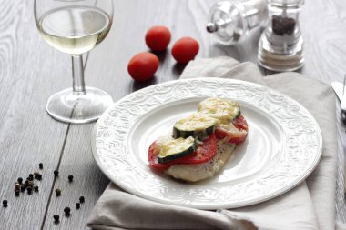 Fırında pişmiş domates, kabak ve peynir bir plaka üzerinde morina balığı fileto