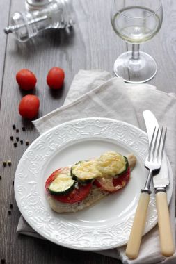 Fırında pişmiş domates, kabak ve peynir bir plaka üzerinde morina balığı fileto