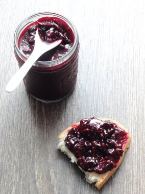 Siyah frenk üzümü reçeli ve ahşap masa ekmek. Metin için yer