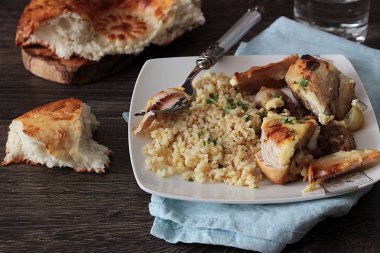 Rustik ahşap zemin üzerinde bir plaka üzerinde elma ve bulgar ile kavrulmuş tavuk budu