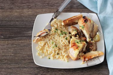 Rustik ahşap zemin üzerinde bir plaka üzerinde elma ve bulgar ile kavrulmuş tavuk budu