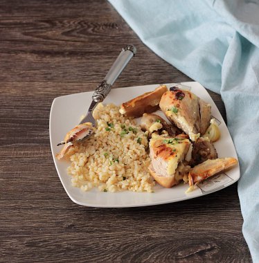 Rustik ahşap zemin üzerinde bir plaka üzerinde elma ve bulgar ile kavrulmuş tavuk budu