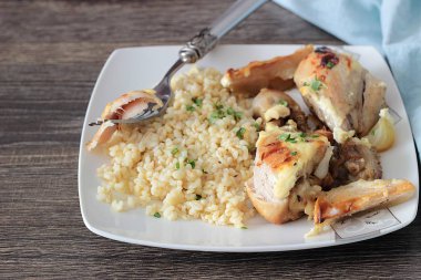 Rustik ahşap zemin üzerinde bir plaka üzerinde elma ve bulgar ile kavrulmuş tavuk budu