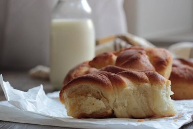 Ahşap masa üzerinde süt şişesiyle taze lezzetli ekmek.