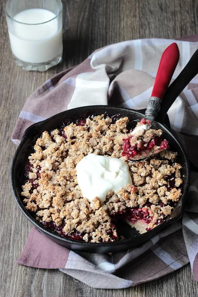 Berry ile yulaf ezmesi gevrek kabuk ahşap arka plan üzerinde dökme demir tavada kremalı kek. Sağlıklı kahvaltı.