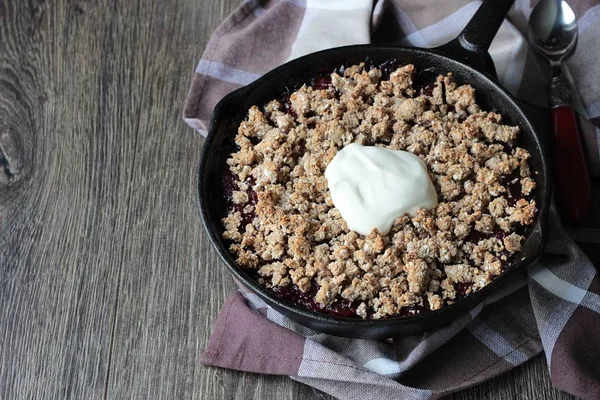 Berry ile yulaf ezmesi gevrek kabuk ahşap arka plan üzerinde dökme demir tavada kremalı kek. Sağlıklı kahvaltı.