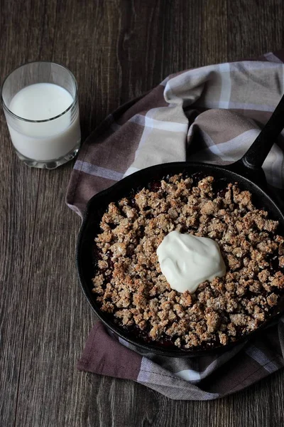 Bogyó crumble zabpehely ropogós kéreg öntöttvas serpenyőben a fa háttér krémmel. Egészséges reggeli. — Stock Fotó