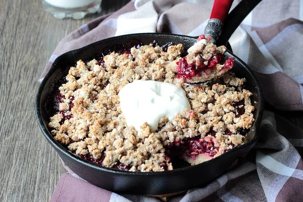 Berry ile yulaf ezmesi gevrek kabuk ahşap arka plan üzerinde dökme demir tavada kremalı kek. Sağlıklı kahvaltı.