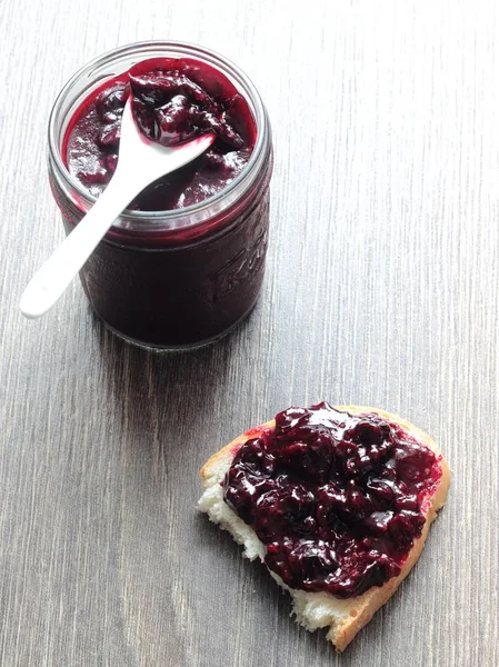 Siyah frenk üzümü reçeli ve ahşap masa ekmek. Metin için yer