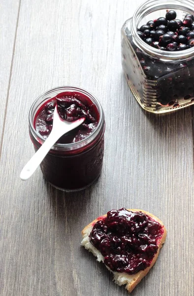 Siyah frenk üzümü reçeli ve ahşap masa ekmek. Metin için yer