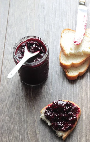 Siyah frenk üzümü reçeli ve ahşap masa ekmek. Metin için yer