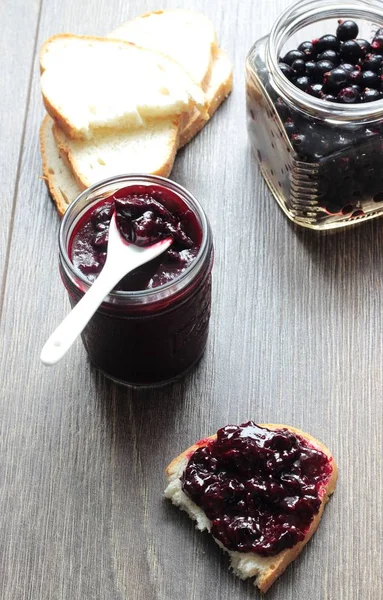 Siyah frenk üzümü reçeli ve ahşap masa ekmek. Metin için yer