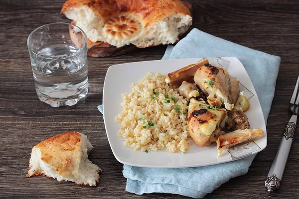 Rustik ahşap zemin üzerinde bir plaka üzerinde elma ve bulgar ile kavrulmuş tavuk budu