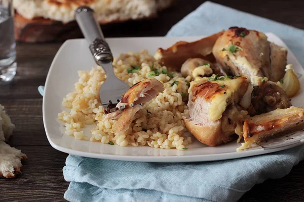 Rustik ahşap zemin üzerinde bir plaka üzerinde elma ve bulgar ile kavrulmuş tavuk budu