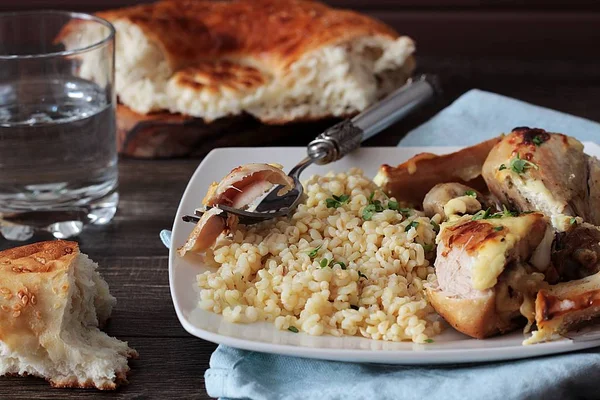 Rustik ahşap zemin üzerinde bir plaka üzerinde elma ve bulgar ile kavrulmuş tavuk budu