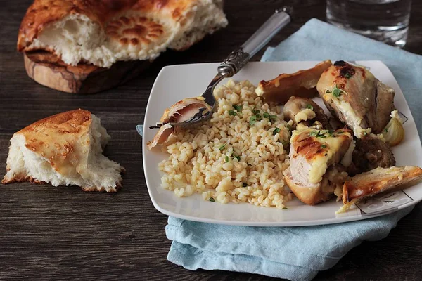 Rustik ahşap zemin üzerinde bir plaka üzerinde elma ve bulgar ile kavrulmuş tavuk budu