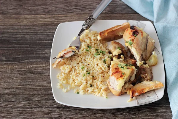 Rustik ahşap zemin üzerinde bir plaka üzerinde elma ve bulgar ile kavrulmuş tavuk budu