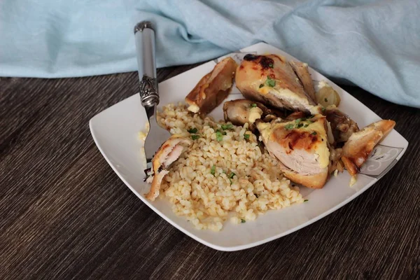 Rustik ahşap zemin üzerinde bir plaka üzerinde elma ve bulgar ile kavrulmuş tavuk budu