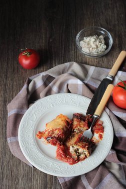 Ahşap bir masa üzerinde peynir Dolum ve domates soslu patlıcan böreği