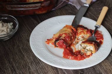 Ahşap bir masa üzerinde peynir Dolum ve domates soslu patlıcan böreği