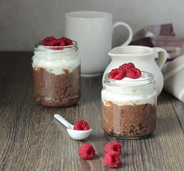 Darı lapası çikolata, krema ve ahududu rustik arka plan ile. Sağlıklı kahvaltı.