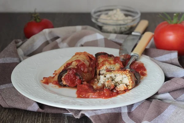 Ahşap bir masa üzerinde peynir Dolum ve domates soslu patlıcan böreği