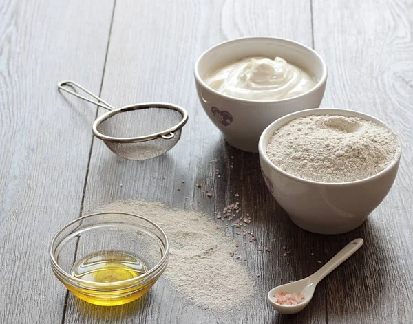 Ingredientes saludables para hornear: harina de centeno, queso cottage, aceite de oliva y sal sobre un fondo de mesa marrón . —  Fotos de Stock