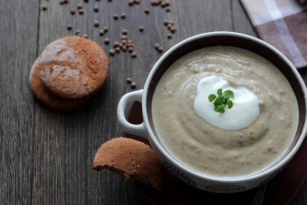 Lentilha e sopa de creme de ervilha com creme, ervas e em um fundo de madeira . — Fotografia de Stock