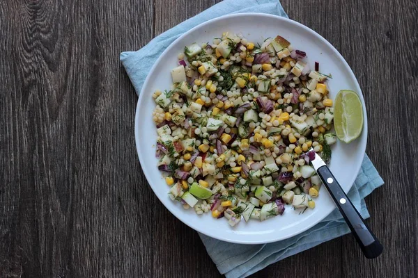 Mısır, elma, kırmızı soğan, peynir ve dereotu ile rustik tabloda lezzetli yaz makarna salatası