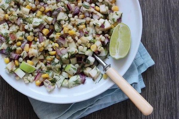 Mısır, elma, kırmızı soğan, peynir ve dereotu ile rustik tabloda lezzetli yaz makarna salatası