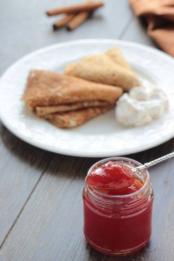 Kırmızı reçel kavanoz ve krep (Rus blini) ekşi krema ve beyaz tabakta reçel ile