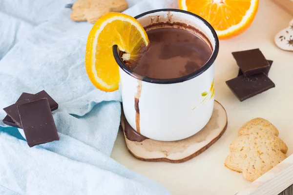 Hot chocolate or cocoa drink with orange and cinnamon stick served with gingerbread cookies and pieces of chocolate.