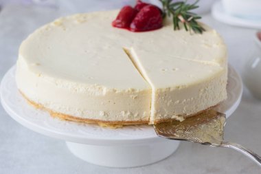 Klasik vanilyalı cheesecake (New York cheesecake) beyaz tabakta çilek sosu ve biberiye ve açık arkaplanlı