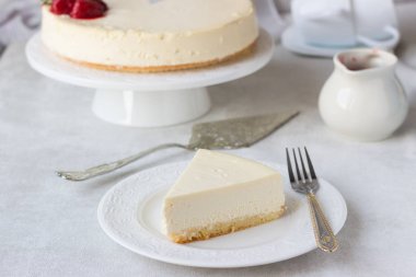 Klasik vanilyalı cheesecake (New York cheesecake) beyaz tabakta çilek sosu ve biberiye ve açık arkaplanlı