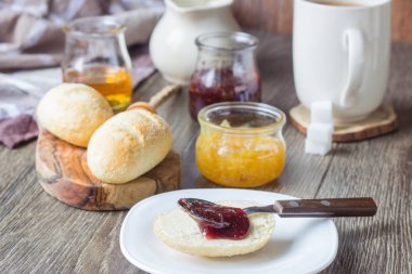 Çörekler, reçel, bal, kahve veya sütlü çay. Kahvaltı kavramı. Rustik ahşap masa üzerinde lezzetli breakfast.