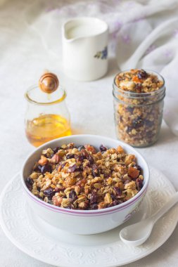 Kahvaltı: taze yulaf granola kase fındık, Kuruyemiş, tohum ve Ballı süt üzerinde hafif bir arka plan ile.