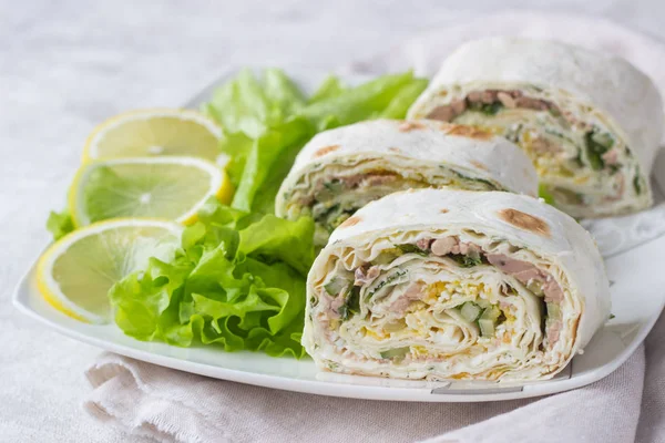 Ton balıklı salata rulo sandviç salata ile beyaz plaka üzerinde bırakır. Ton balığı, salatalık, yumurta ve dereotu ile rulo sandviç. İnce Ermeni pide veya silindir Mini değirmenler. Aperatif.