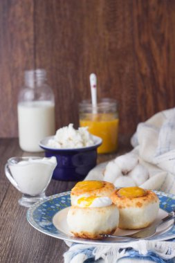 Ekşi krema ve portakal reçeli ile bir plaka üzerinde süzme peynir krep. Syrniki. Geleneksel Rus Mutfağı