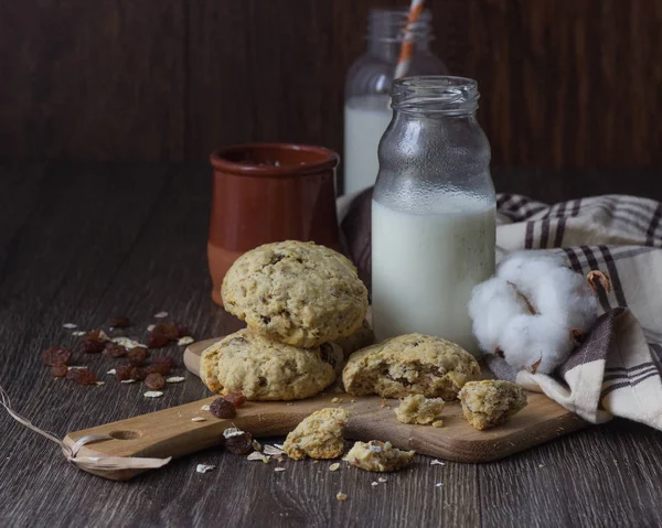 燕麦葡萄干饼干木砧板 瓶牛奶和燕麦片罐 — 图库照片