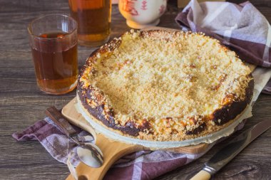 Süzme peynir ve kahverengi bir arka plan üzerine bir bardak çay ile keten peçete üzerinde (geleneksel Rus pasta vatrushka, lor tart) kek ile ev yapımı açık pasta.