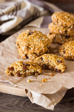 Yulaf ezmeli kurabiye (bisküvi) ahşap kesme tahtası üzerinde kuru üzüm ve susam tohumu ile. Sağlıklı yulaf kurabiye.