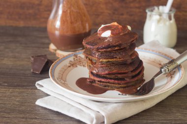 Plaka üzerinde yoğurt ve çikolata soslu çikolatalı kırmızı kadife krep yığını.