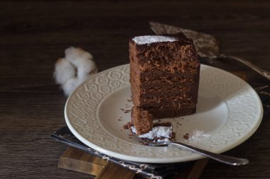 Karanlık bir arka plan üzerinde beyaz bir plaka üzerinde çikolata ganache çikolata tatlım pastasından çikolata custard ile kaplı.