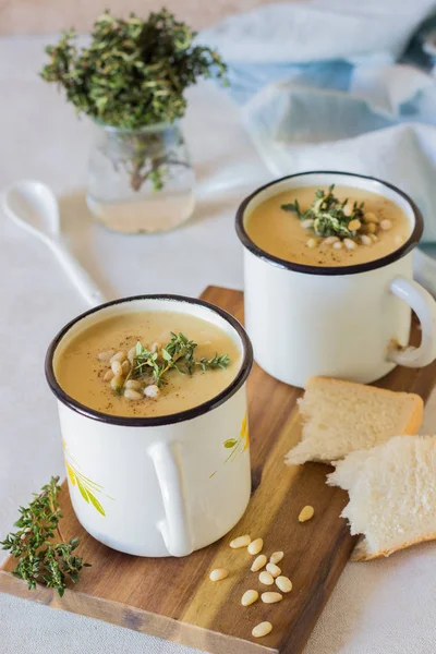 Soup, orange cream of pumpkin, carrot and lentil soup in mug served with pine nuts and thyme. Winter and autumn vegetarian food concept. — Stock Image Soup Orange Cream Pumpkin Carrot Lentil Soup Mug Served Pine Stock Image