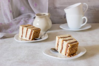 Ekşi krema bir beyaz plaka ve açık renkli çikolata ve beyaz katmanlarla ile şifon pasta dilimi